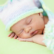 adorable baby weared cap sleeping on green