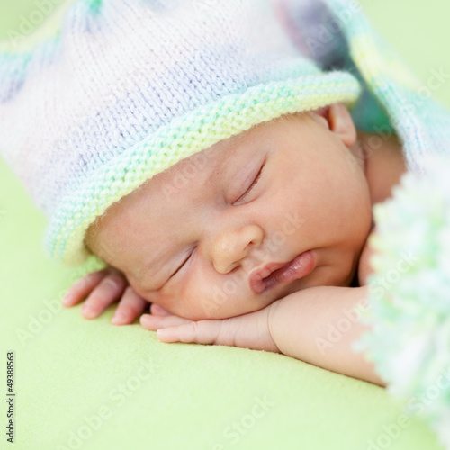 Photo: adorable baby weared cap sleeping on green adorable baby weared cap sleeping on green
