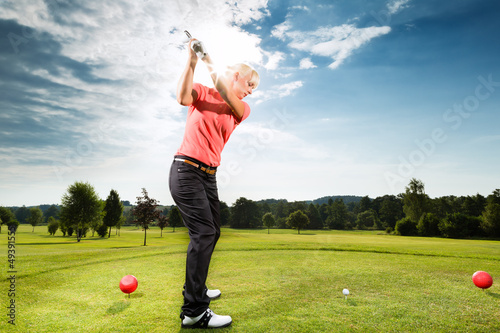 Foto: Young golf player on course doing golf swing Young golf player on course doing golf swing