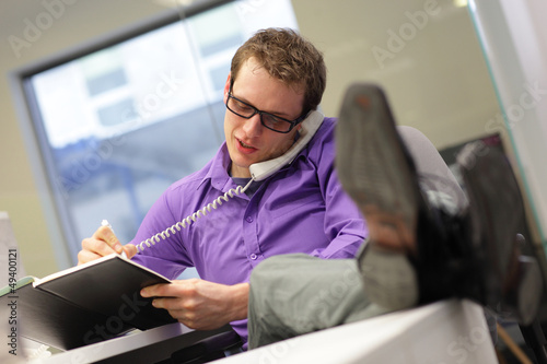 Photo: businessman on phone - bad sitting posture businessman on phone - bad sitting posture