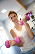 Happy woman in gym lifting dumbbells
