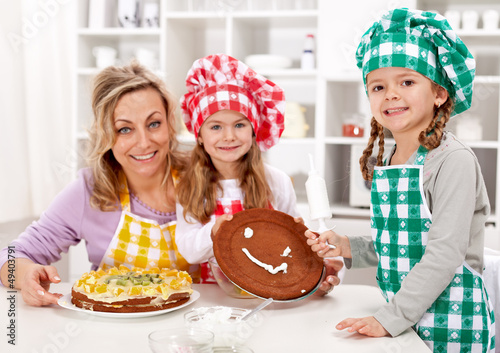 Photo: Little chef girls with their mother making a cake Little chef girls with their mother making a cake