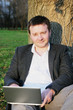 Man with laptop under a tree
