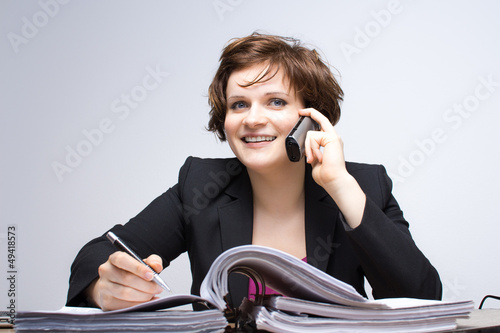 Photo: Junge Geschäftsfrau telefoniert am Arbeitsplatz Junge Geschäftsfrau telefoniert am Arbeitsplatz