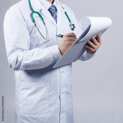 Photo: Male doctor fills patient card Male doctor fills patient card