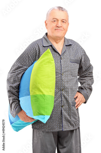 Photo: A smiling mature man in pajamas holding a pillow A smiling mature man in pajamas holding a pillow
