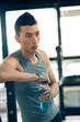 Young asian man having a rest drinking a beverage in the gym.