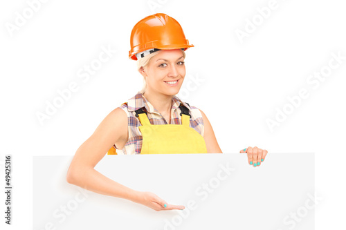 Photo: Female manual worker standing behind blank panel and gesturing Female manual worker standing behind blank panel and gesturing