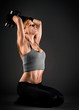 Fit woman holding weights over a dark background