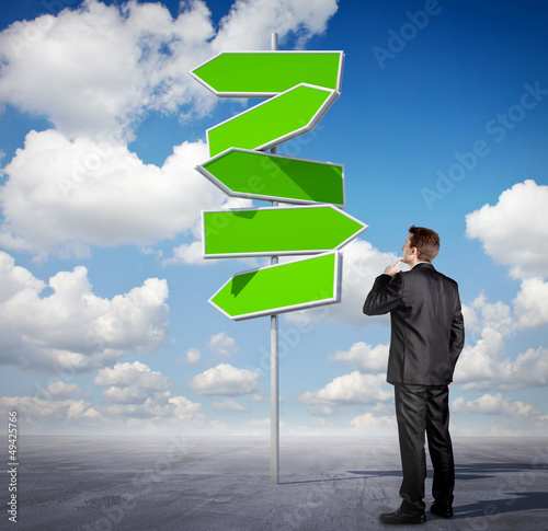 Photo: Businessman looking at an arrow sign Businessman looking at an arrow sign