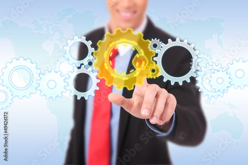 Photo: business man pushing a cog button business man pushing a cog button
