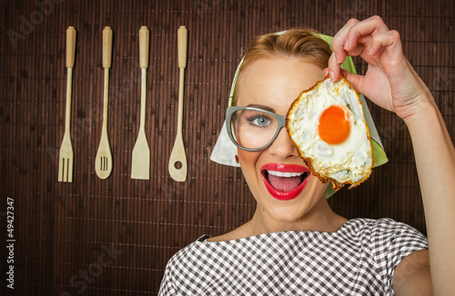 Photo: Happy funny woman cook holding pan with fried egg - close up Happy funny woman cook holding pan with fried egg - close up