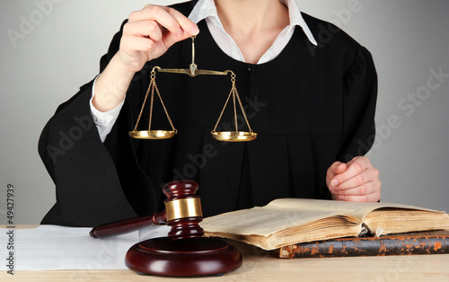 Photo: Judge sitting at table during court hearings on grey background Judge sitting at table during court hearings on grey background