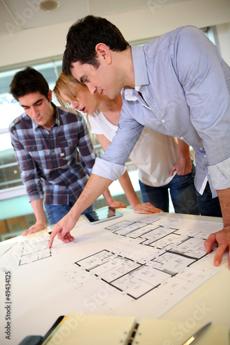 Photo: Startup business team working on blueprint Startup business team working on blueprint