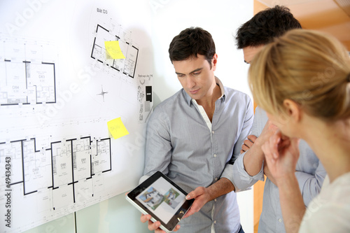 Photo: Architects in office looking at construction project Architects in office looking at construction project
