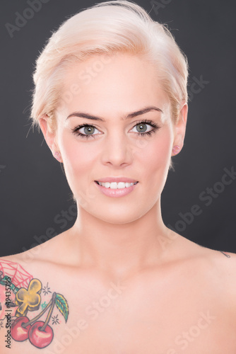 Photo: Young and smiling woman in front of grey background Young and smiling woman in front of grey background