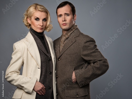 Photo: Elegant couple in coats isolated on grey Elegant couple in coats isolated on grey