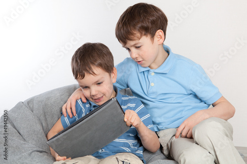 Photo: Two brothers playing on tablet Two brothers playing on tablet
