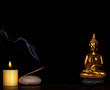 Meditation - golden buddha, candle and incense stick over black