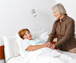 Alte kranke Frau wird von Seniorin besucht