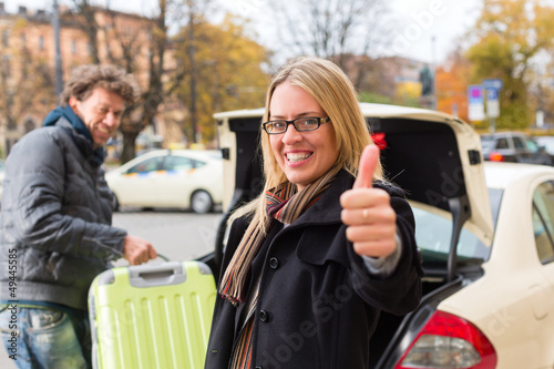 Photo: Young woman in front of taxi Young woman in front of taxi