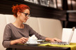 Businesswoman sitting at table in cafe using notebook. 