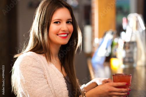 Photo: Woman having a drink in a pub Woman having a drink in a pub