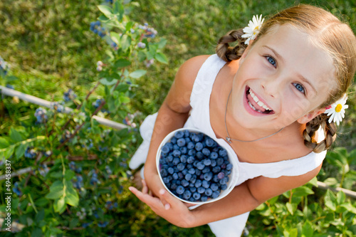 Photo: Blueberries - Girl with ripe blueberries in the garden Blueberries - Girl with ripe blueberries in the garden