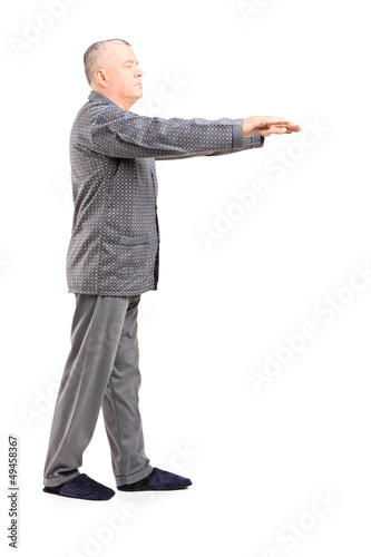 Photo: Full length portrait of a mature man in pajamas sleepwalking Full length portrait of a mature man in pajamas sleepwalking