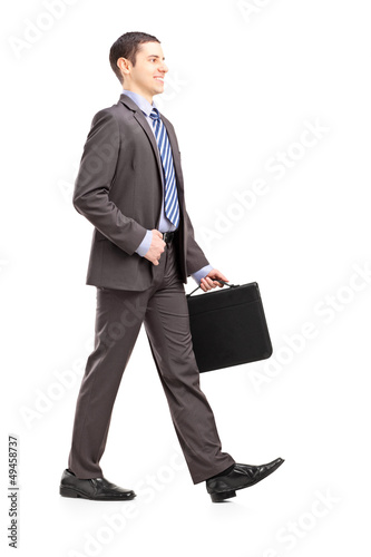 Photo: Full length portrait of a young businessman with briefcase walki Full length portrait of a young businessman with briefcase walki
