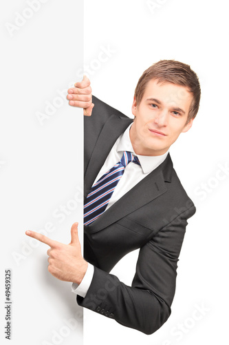 Photo: Young handsome businessman pointing on a blank panel Young handsome businessman pointing on a blank panel