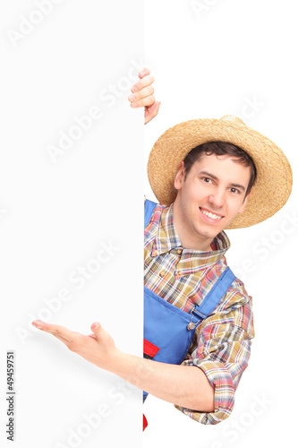 Photo: Young smiling farmer gesturing on a blank panel Young smiling farmer gesturing on a blank panel