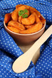 Appetizing village potatoes in bowl on blue fabric close-up