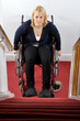 Junge Frau im Rollstuhl vor Treppe als Hindernis
