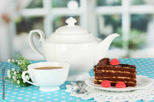 Photo: Teapot, cup of tea and delicious cake on window background Teapot, cup of tea and delicious cake on window background