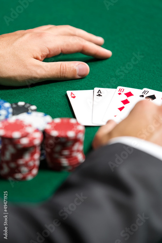 Photo: Poker player opens his cards. Risky entertainment of gambling Poker player opens his cards. Risky entertainment of gambling