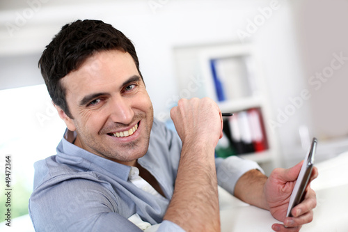 Photo: Smiling guy connected on smartphone Smiling guy connected on smartphone