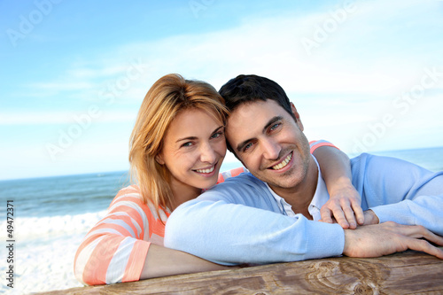 Photo: Happy couple leaning on a fence by the sea Happy couple leaning on a fence by the sea