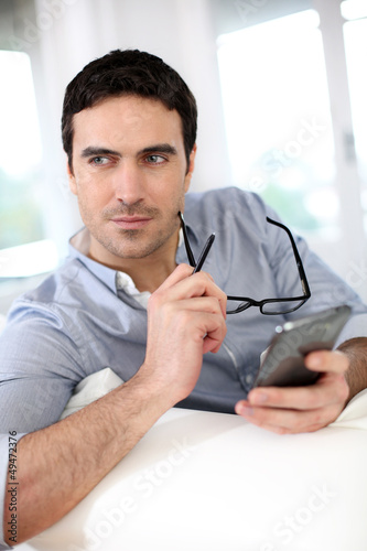 Photo: Man sitting in sofa and using smartphone Man sitting in sofa and using smartphone