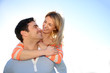 Man giving piggyback ride to girlfriend by the sea