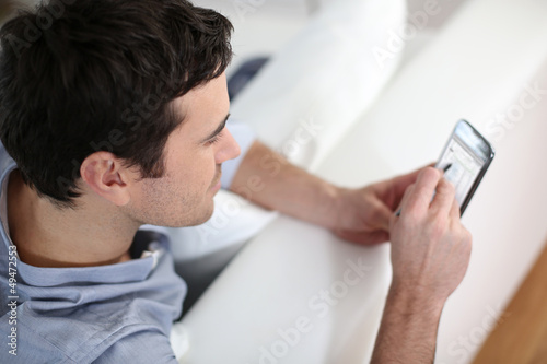 Photo: Upper view of man in sofa using smartphone Upper view of man in sofa using smartphone