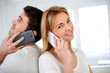 Couple using smartphone, sitting back to back