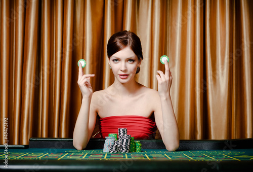 Photo: Woman with chips sitting at the roulette table at the casino Woman with chips sitting at the roulette table at the casino