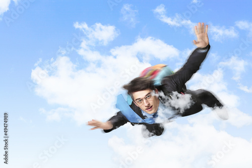 Photo: Young businessman flying with parachute on back Young businessman flying with parachute on back