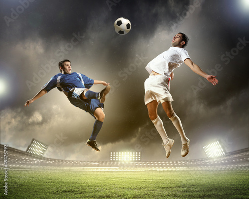 Photo: two football players striking the ball two football players striking the ball