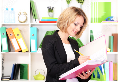 Photo: Beautiful young business woman working in office Beautiful young business woman working in office