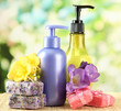 Liquid and hand-made soaps on wooden table, on green background