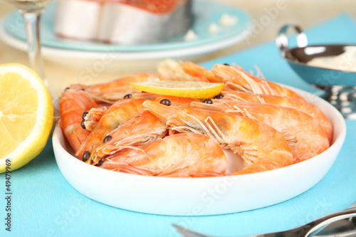 Photo: Shrimps with lemon on plate on wooden table close-up Shrimps with lemon on plate on wooden table close-up