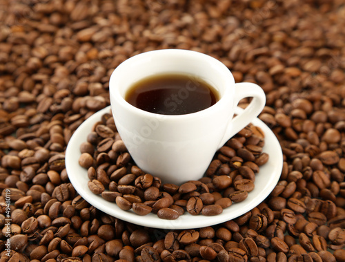 Photo: Cup of coffee on coffee beans background Cup of coffee on coffee beans background