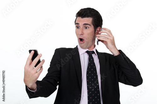 Photo: businessman holding two cell phones businessman holding two cell phones